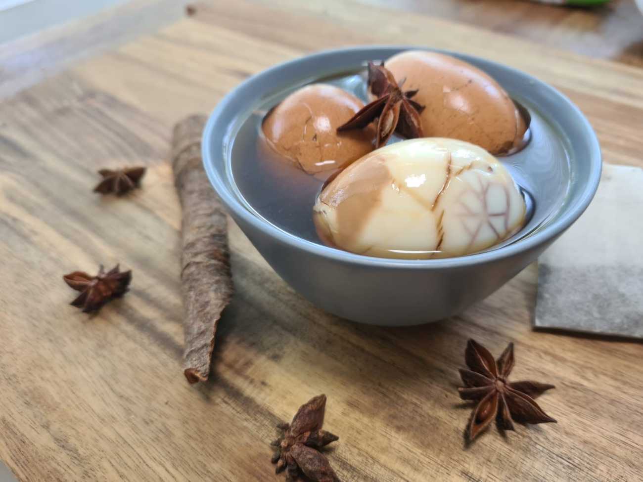 Marinated eggs in a bowl with cinnamon and star anise