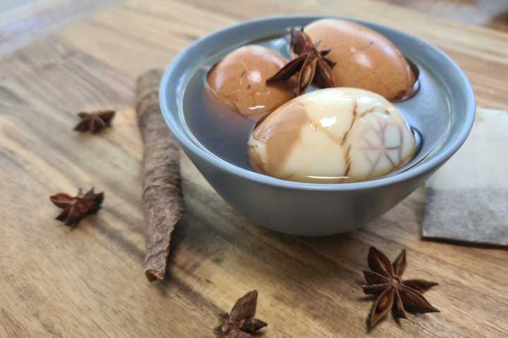 Marinated eggs in a bowl with cinnamon and star anise