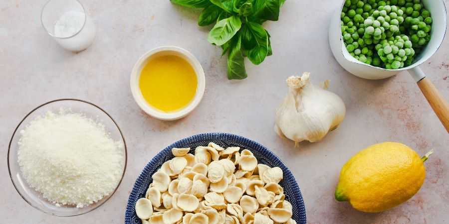 Ingredients for creamy pea pasta on grey backround.