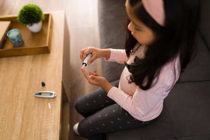 Child with diabetes using a digital monitor to test her blood sugar levels.