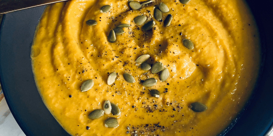 Chickpea pumpkin soup with seeds and pepper on top.