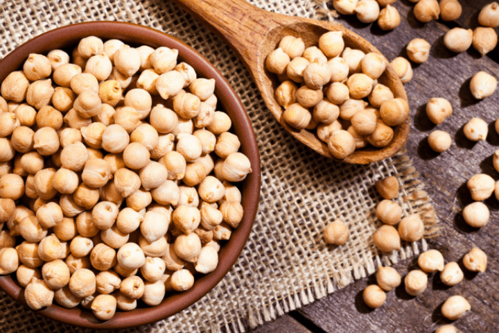 Chickpeas in a bowl next to a wooden spoon