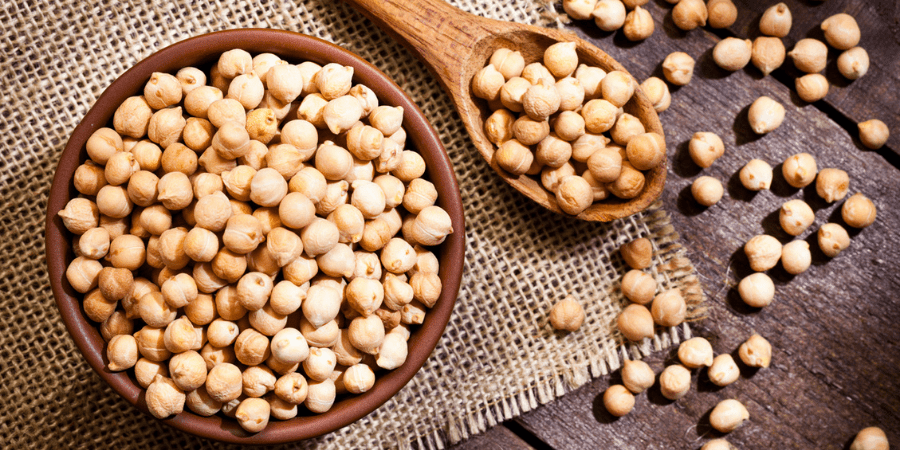 Chickpeas in a bowl next to a wooden spoon