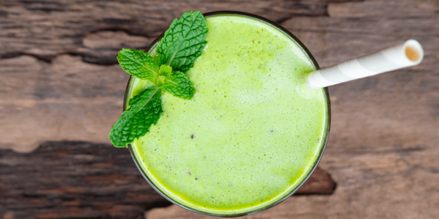Green smoothie drink in a glass with a straw