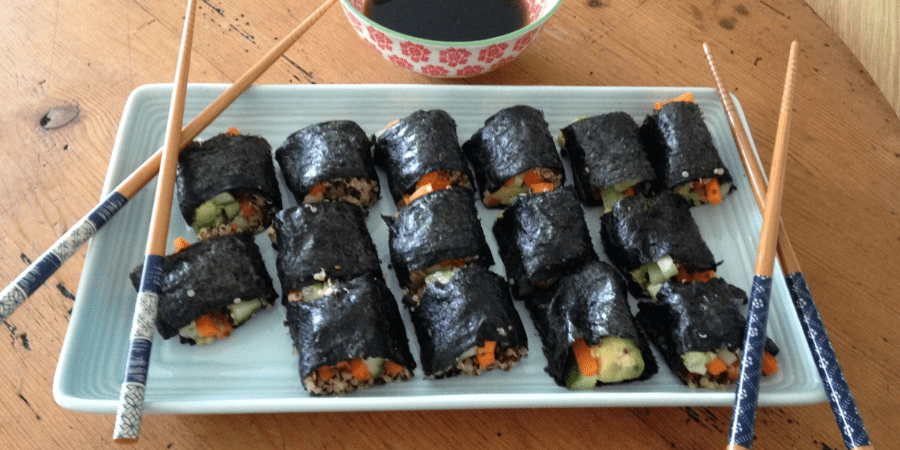 A plate of sushi with chopsticks and soy sauce.