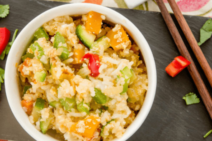 Rice and vegetables in a bowl on a black platter