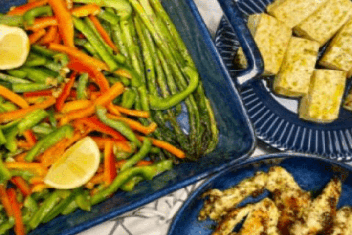Roasted winter vegetables on a black platter with grilled tofu and chicken