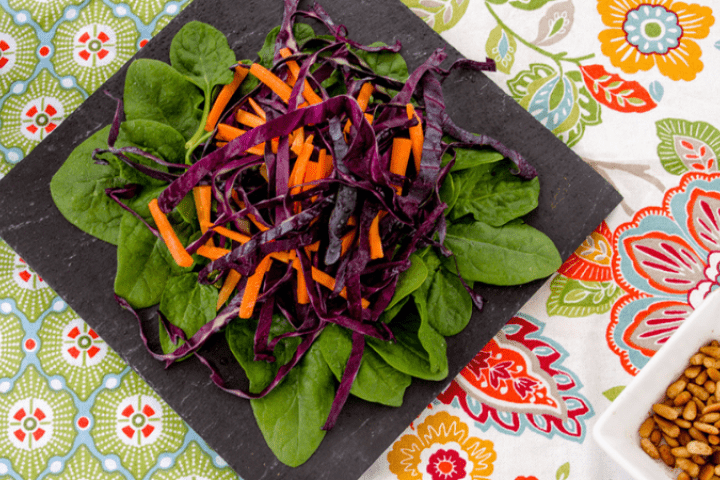 Grated cabbage and carrot on spinach on a black plate